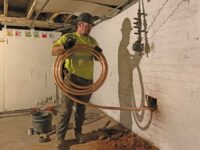 When replacing a customer-side lead or galvanized steel service line, a small hole is drilled through the basement wall prior to pulling the copper line from the inside below ground and out to the curb stop connection.