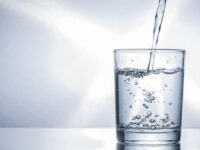 Pouring purify fresh drink water into a glass on table